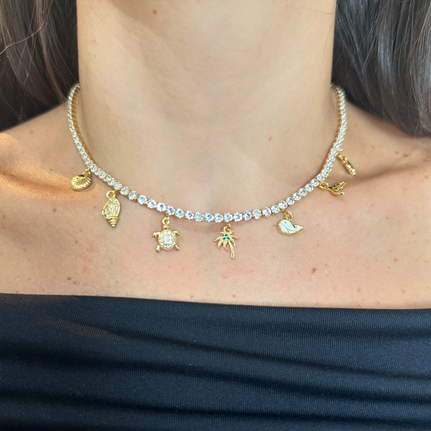 Collar bañado en Oro estilo tennis con dijes playeros guindando.